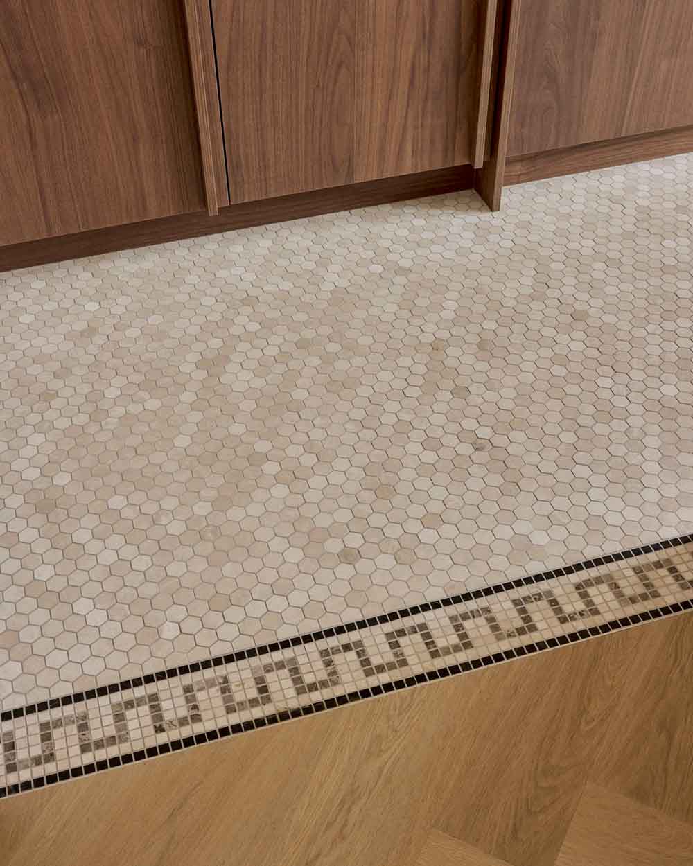 Home – Marcel Lebesque Concepts Detail van een maatwerk vloerafwerking: hexagon-mozaïek met decoratieve sierrand naast eiken parket